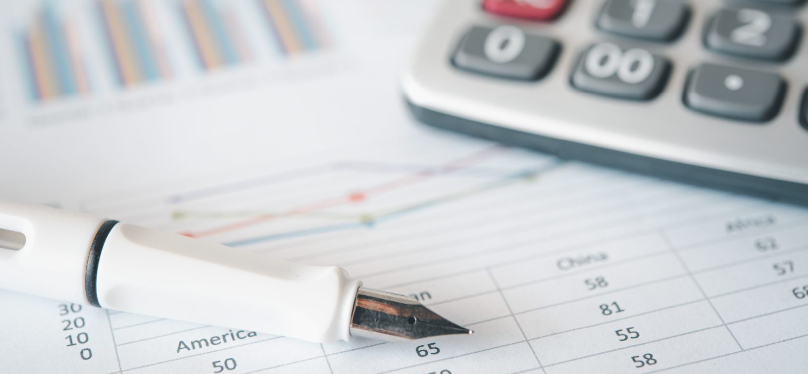 Un imagen con una hoja contable de facturas, una calculadora y una pluma estilográfica